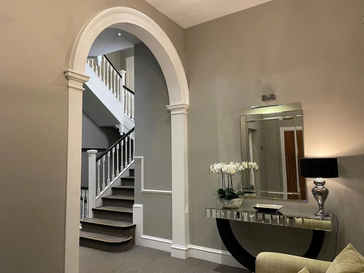 a hallway with a spiral staircase with a mirror at The Craibstone Suites in Aberdeen