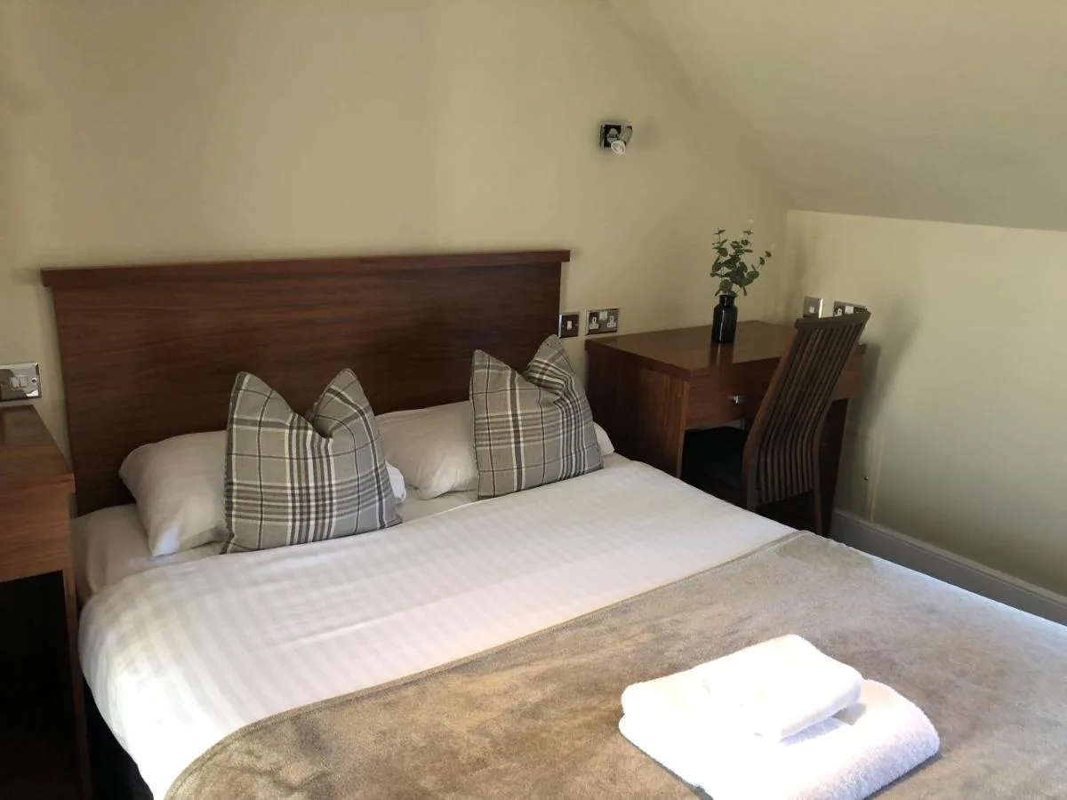 a bedroom with a bed with a wooden headboard and a desk at The Craibstone Suites in Aberdeen